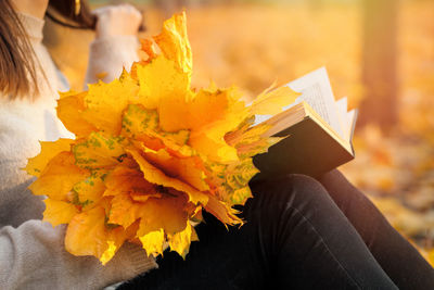 Midsection of woman holding autumn leaves