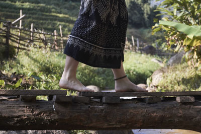 Low section of barefoot woman on footbridge