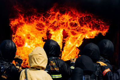 Rear view of firefighters against fire