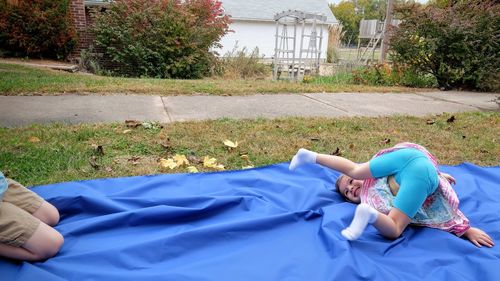 Girl playing on blue sheet in yard