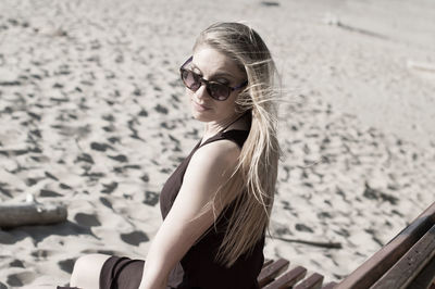 Woman wearing sunglasses while sitting at beach