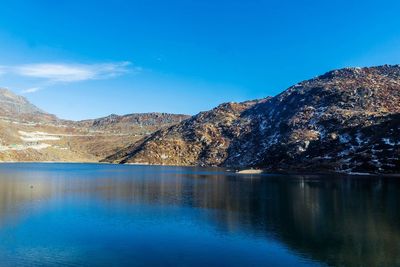 Scenic view of lake and mountains against blue sky