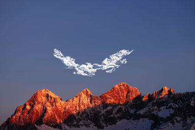 Low angle view of snowcapped mountain against blue sky