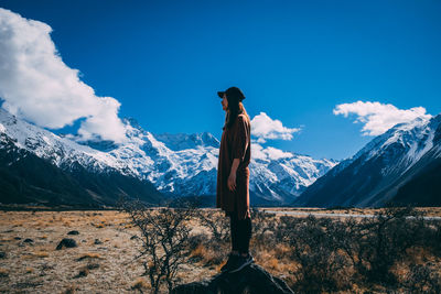 Man standing on snowcapped mountain against sky