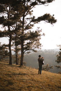 Man photographing while standing on land in forest