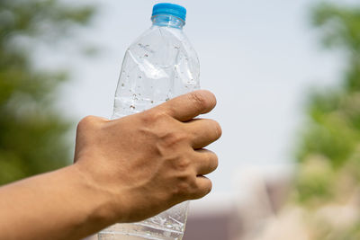 Close-up of hand holding bottle against blurred background