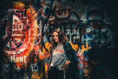 Full length of young woman standing against graffiti wall