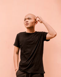 Low angle view of young man looking away against white background