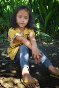 A cute little girl with curly hair on a leaf background