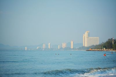 Sea by buildings against clear sky