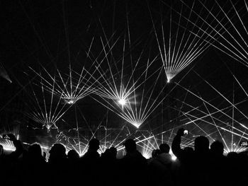 Silhouette people watching laser show at night