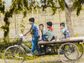 People sitting by bicycle against plants