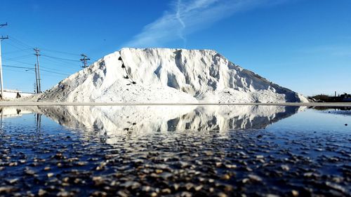 Surface level of salt heap by puddle against sky