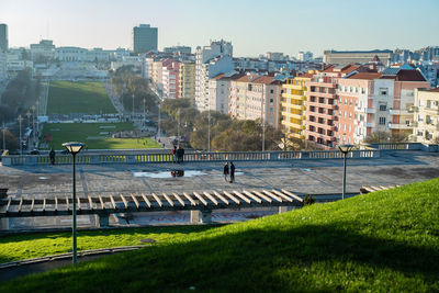 People on street by buildings in city against sky