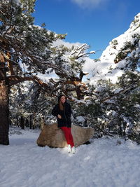 Full length of woman standing on snow covered tree