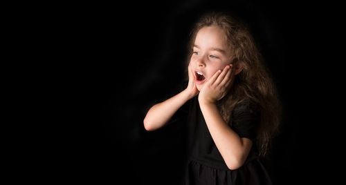 Portrait of girl standing against black background