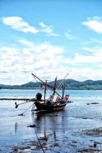 Fishing boat moored in sea against sky