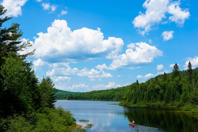 Scenic view of small canoe on lake against cloudy sky