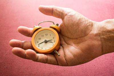 Close-up of hand holding alarm clock above seat