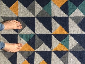 Low section of woman standing on carpet at home