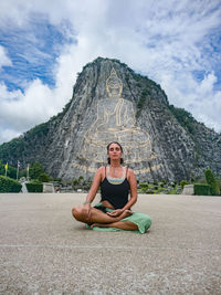 Portrait of woman meditating in front of mountain against sky