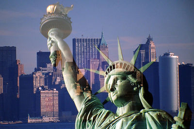 Double exposure image of statue of liberty and cityscape against sky