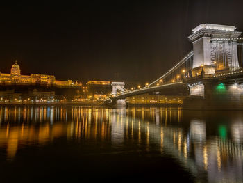 Illuminated bridge over river at night