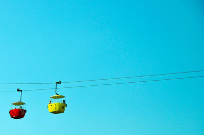 Low angle view of overhead cable car against clear blue sky