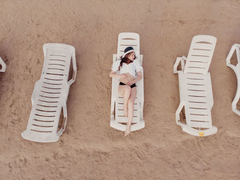 Aerial view of slim woman sunbathing lying on a beach chair