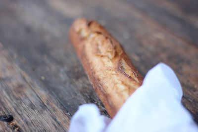 Close-up of hand holding bread on wood