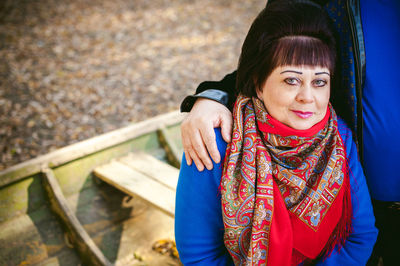 Portrait of mature couple sitting in forest during autumn