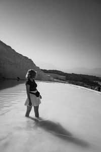 Woman standing in hot spring against clear sky