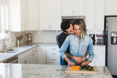 Smiling young woman standing in kitchen at home