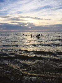 Silhouette people on beach against sky during sunset