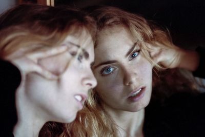 Close-up portrait of young woman with reflection in mirror