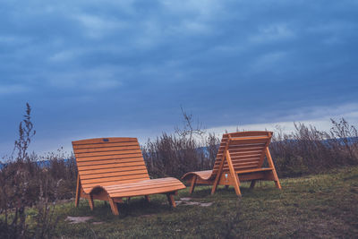 Empty chairs on field against sky