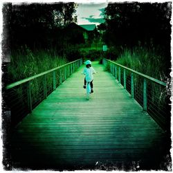 Rear view of woman standing on footbridge