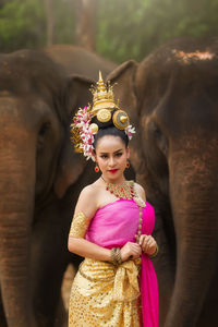 Female in traditional clothing sitting by elephants