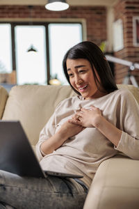 Smiling woman with hand on chest doing video call on laptop