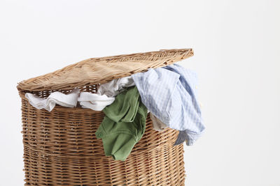 Close-up of clothes in laundry basket over white background