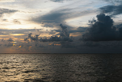 Scenic view of moody sky and clouds over the water during sunset 