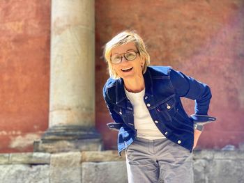 Portrait of a smiling young woman standing against brick wall