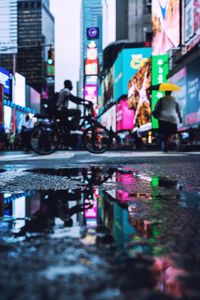 Reflection of people in puddle on street