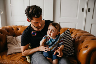 Father and son sitting on sofa