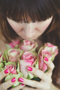 Close-up of woman smelling pink roses