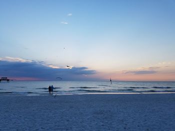 Silhouette man standing on beach against sky during sunset