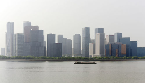 Modern buildings by river against clear sky