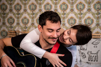 Woman hugs her boyfriend while he is playing the guitar. concept of happy couple life and love.