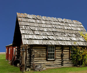 Exterior of abandoned house on field against clear sky