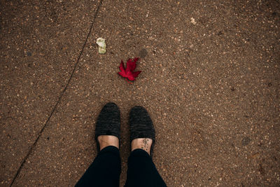 Woman looking at a red leaf on a wet autumn day from above